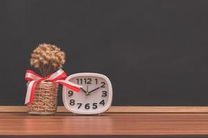 Clock and flower pot on the table photo