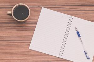 Notebook and pen on wooden table top view photo