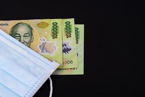 Face mask with Vietnamese money on black background photo