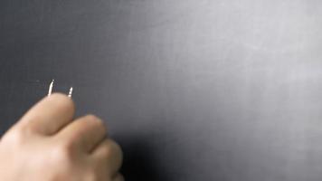 close-up de uma mão segurando um giz e escrevendo olá na lousa