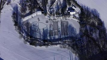 Vista aérea de arriba hacia abajo del lago congelado con gente patinando en un día soleado de invierno en 4 k video