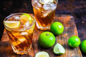 Iced tea and sliced limes on a wood tray on a wooden table photo