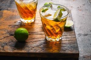 Iced tea and sliced limes on a wood tray on a wooden table photo