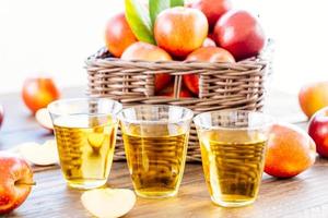 jugo de manzana en vasos y manzanas en la canasta foto