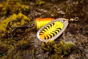 Fishing spoon lure on wet stone with moss photo