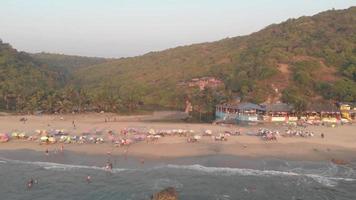 Turistas disfrutando del océano en la playa de Arambol, en Goa, India - Toma aérea de vuelo video