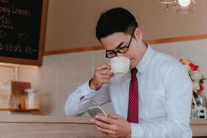 Businessman drinking coffee and looking at his phone photo