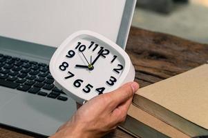 Hand holding a clock at the work desk photo