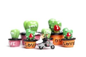 Miniature couple riding a motorcycle next to miniature succulent plants, Valentine's Day concept photo