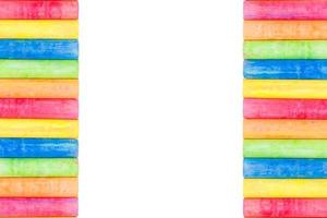 Rows of rainbow-colored chalk isolated on a white background photo