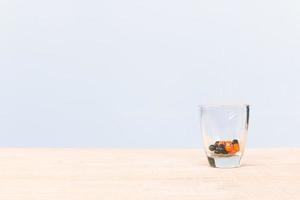 Pill in a glass on a wooden floor and concrete background