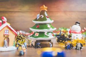 Miniature people creating Christmas decorations on a wooden background photo