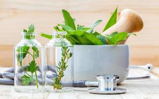 Fresh herbs for essential oils in bottles and a mortar photo