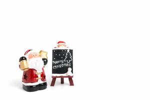 Santa Claus figurine with a miniature chalkboard with Merry Christmas text on a white background photo