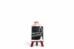 Santa Claus figurine with a miniature chalkboard with Merry Christmas text on a white background photo