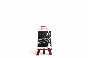 Santa Claus figurine with a miniature chalkboard with Merry Christmas text on a white background photo