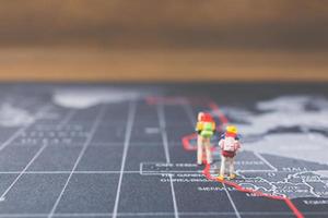 Miniature backpackers walking on a world map, tourism and travel concept photo