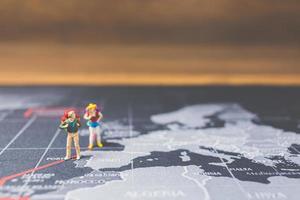 Mochileros en miniatura caminando sobre un mapa del mundo, concepto de turismo y viajes