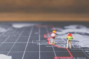 Miniature backpackers walking on a world map, tourism and travel concept photo