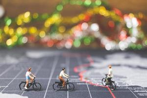 Miniature travelers riding a bicycle on a world map, traveling and exploring the world concept photo