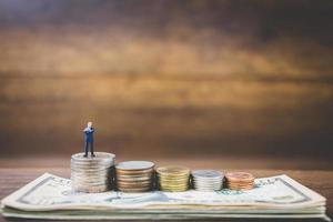 Miniature businessmen on money on a wooden background photo