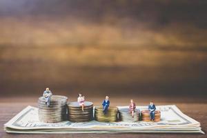 Miniature businessmen on money on a wooden background photo
