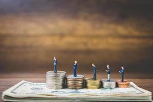 Miniature businessmen on money on a wooden background
