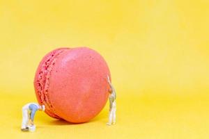 Miniature painters coloring macaroons on a yellow background photo