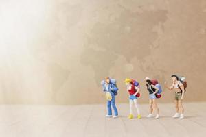 Miniature travelers with backpacks walking on a map, travel and adventure concept photo