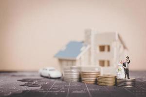 Miniature bride and groom with coins in front of a home, successful family concept photo