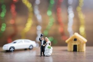 Miniature bride and groom on a wooden floor with colorful bokeh background, successful family concept photo