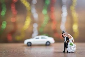 Miniature bride and groom on a wooden floor with colorful bokeh background, successful family concept photo