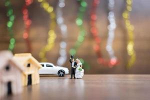 Miniature bride and groom on a wooden floor with colorful bokeh background, successful family concept photo