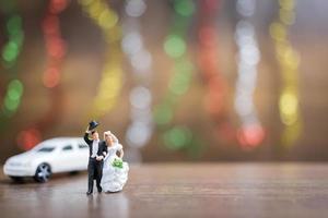 Miniature bride and groom on a wooden floor with colorful bokeh background, successful family concept photo