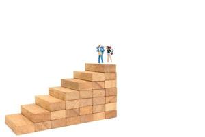 Miniature backpackers standing on wood blocks isolated on a white background, travel concept photo