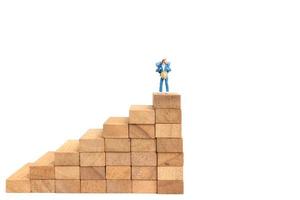 Miniature backpacker standing on wood blocks isolated on a white background, travel concept photo