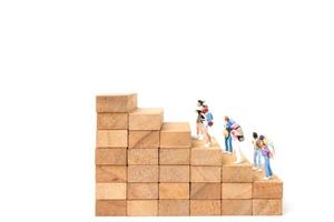 Miniature backpackers standing on wood blocks isolated on a white background, travel concept photo