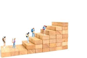 Miniature backpackers standing on wood blocks isolated on a white background, travel concept photo