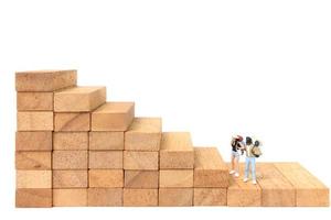 Miniature backpackers standing on wood blocks isolated on a white background, travel concept photo