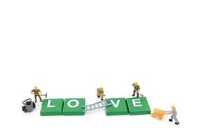 Trabajadores en miniatura construyendo la palabra amor sobre un fondo blanco. foto