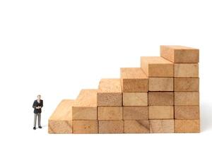 Miniature businesspeople standing on wood blocks isolated on a white background photo