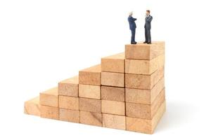 Miniature businesspeople standing on wood blocks isolated on a white background photo