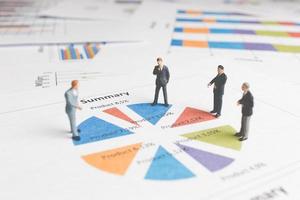 Miniature businessmen standing on a paper graph chart, developing teamwork concept photo