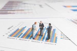 Miniature businessmen standing on a paper graph chart, developing teamwork concept photo