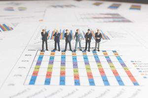 Miniature businessmen standing on a paper graph chart, developing teamwork concept photo