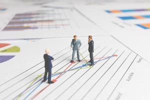 Miniature businessmen standing on a paper graph chart, developing teamwork concept photo