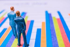 Miniature businessmen standing on a paper graph chart, developing teamwork concept photo