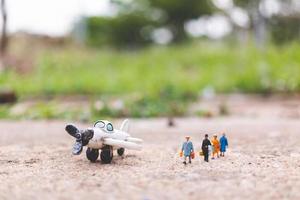 Miniature travelers holding carry-on luggage getting on a plane, exploring the world concept photo