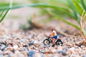 Viajero en miniatura en bicicleta, explorando el concepto del mundo. foto