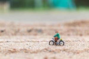 Viajero en miniatura en bicicleta, explorando el concepto del mundo. foto